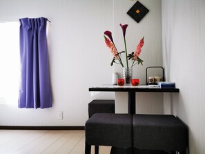 A modern room with a dining table, two chairs, a vase with flowers, and a wall-mounted record player.
