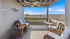 A covered porch with wicker furniture, a ceiling fan, and a view of the landscape.