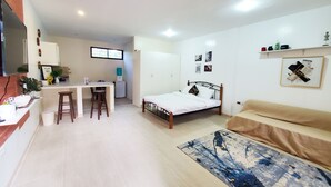 A compact living space with a kitchenette, a bed, a sofa, and a dining area.
