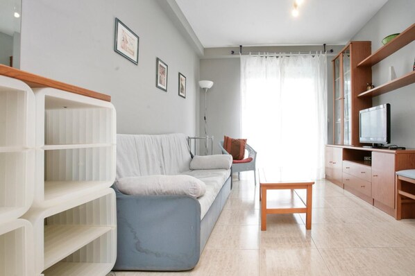 Un salon moderne avec un canapé, un fauteuil, un téléviseur et des étagères intégrées.