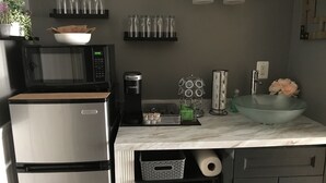 A modern kitchen with a stainless steel refrigerator, a microwave, a coffee maker, and a sink with a marble countertop. - Spacious suite with private patio, minutes from DC / DCA (Arlington)