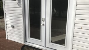 A white exterior door with a glass panel, a keypad lock, and a small outdoor light fixture above it. - Spacious suite with private patio, minutes from DC / DCA (Arlington)