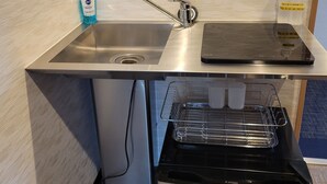 A kitchen with a stainless steel sink, a dish drying rack, and a dishwasher.