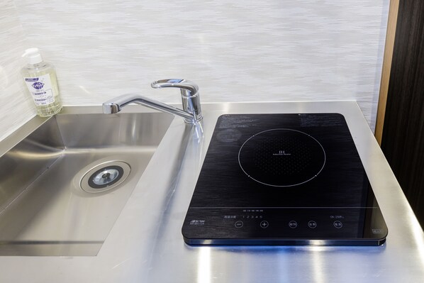 Une cuisine moderne dotée d’un évier en acier inoxydable, d’une plaque de cuisson à induction noire et d’un flacon de savon liquide.