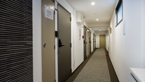 A hotel hallway with doors, a fire extinguisher, and a sign on the wall.
