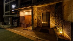 A hotel entrance with a stone facade, an elevator, and a sign indicating the name "KYOTO".