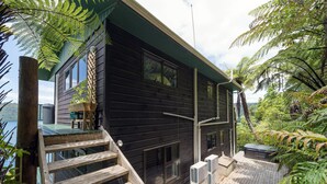 Een modern houten huis met terras, grote ramen en een jacuzzi.