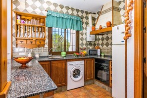 Een kleine keuken met een wasmachine, een magnetron en een spoelbak.