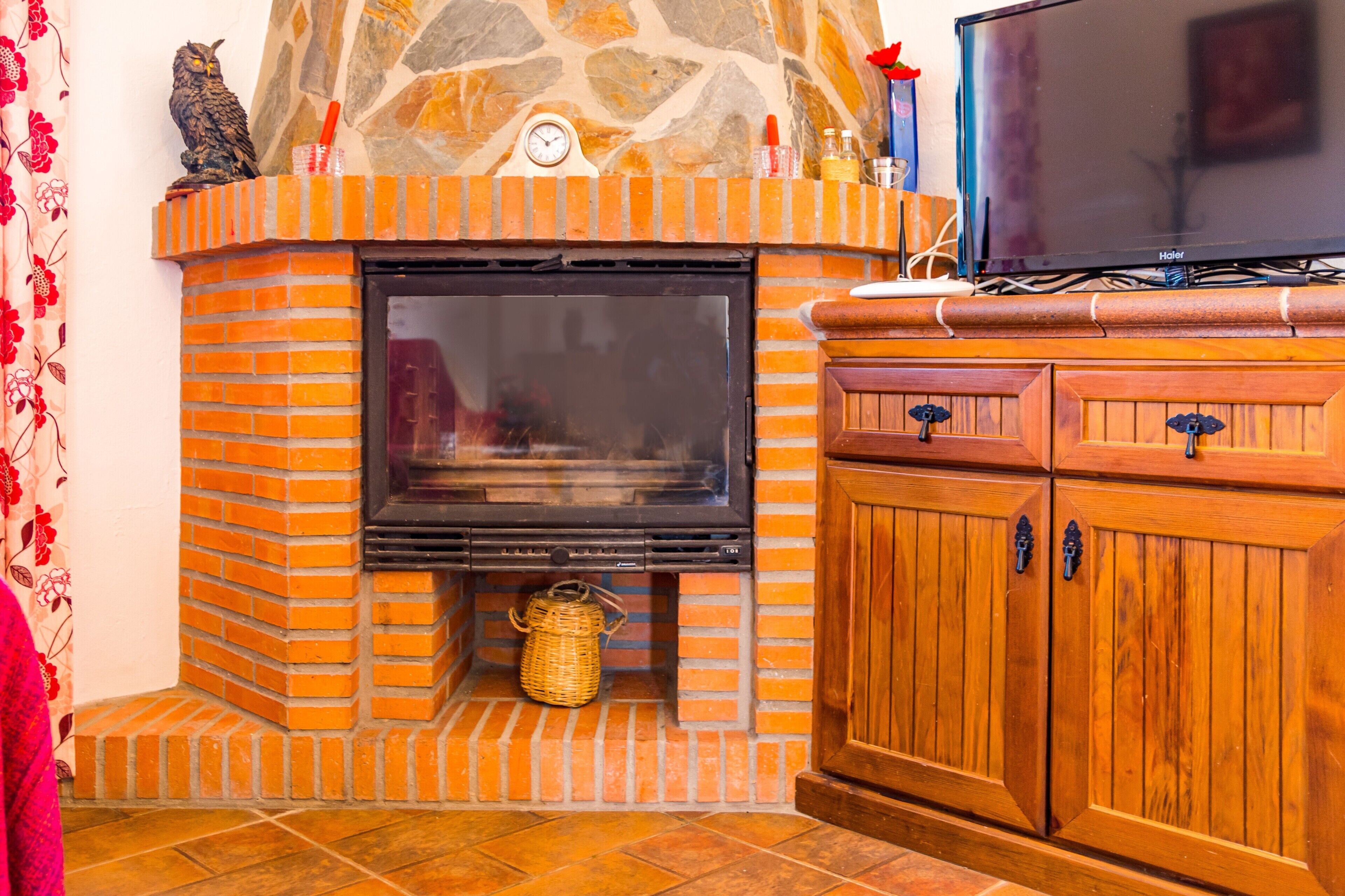 A fireplace with a stone mantle, a television on top, and a wooden cabinet below.