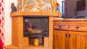 A fireplace with a stone mantle, a television on top, and a wooden cabinet below. - Charming Home with Pool, Spacious Terrace, Garden & Wi-Fi; Pets Allowed, Parking Available (Conil de la Frontera)