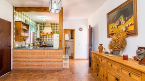 A kitchen with a brick backsplash, wooden cabinets, a tiled floor, and a painting on the wall. - Charming Home with Pool, Spacious Terrace, Garden & Wi-Fi; Pets Allowed, Parking Available (Conil de la Frontera)