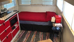 A compact RV interior with a kitchenette, a bed, and a TV mounted above the windows. - 1950's Retro experience.  Classic RV.  (SCOTTDALE)