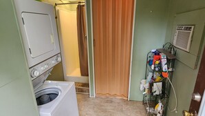 A laundry room with a washing machine, a drying rack, and a door with a sign. - 1950's Retro experience.  Classic RV.  (SCOTTDALE)