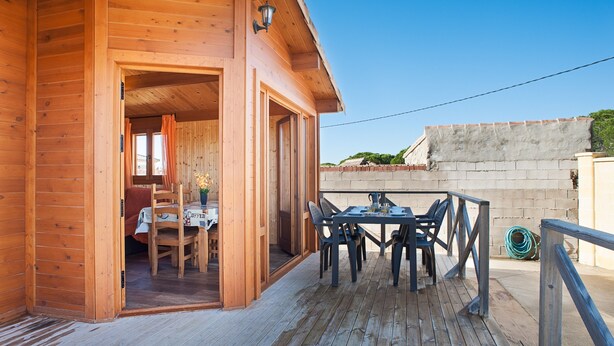 Une cabane en bois dotée d’une terrasse, d’une table à manger avec des chaises et offrant une vue sur les environs.