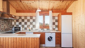 Une cuisine compacte avec des murs en bois, un pare-feu en carrelage, un lave-linge et un réfrigérateur.