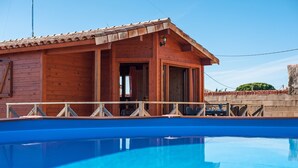 Une cabane en bois avec une piscine, un balcon et un ciel d’un bleu éclatant.