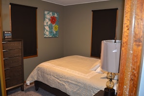 Ein Schlafzimmer mit einem Bett, einem Schminktisch, einer Lampe und einem Bild an der Wand.