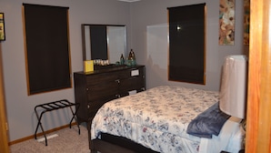 A bedroom with a bed, dresser, mirror, and two windows. - The Farmhouse...only in town! (Sergeant Bluff)