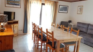Un coin repas avec une table et des chaises en bois, un canapé, un téléviseur et des tableaux encadrés accrochés aux murs.