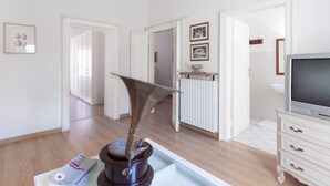 Ein modernes Wohnzimmer mit Fernseher, einer dekorativen Metallskulptur und einem weißen Schrank.