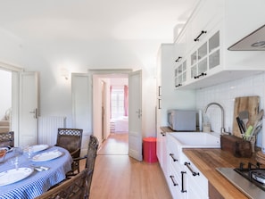 A kitchen with white cabinets, a microwave, and a wooden cutting board.
