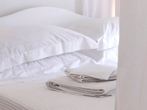 A neatly made bed with white bedding and a folded towel.