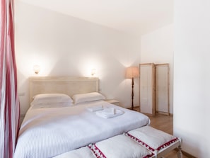 A bedroom with a bed, bedside lamps, a nightstand, and a mirror.