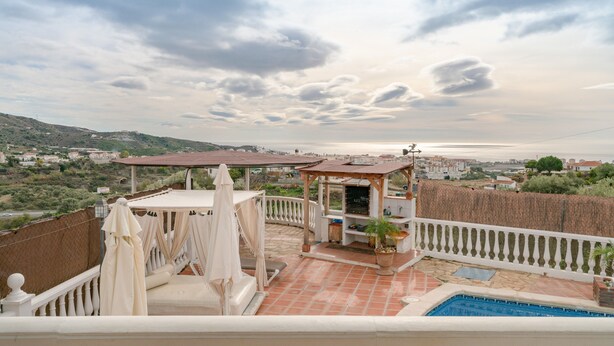 Una terrazza con piscina, arredi da esterno e vista mare.