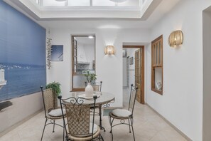 A dining area with a round table, four chairs, a vase, and a potted plant.