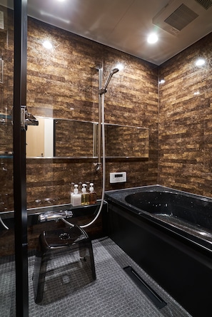 Un baño moderno con una bañera negra, cabina de ducha con mampara de vidrio y un espejo.
