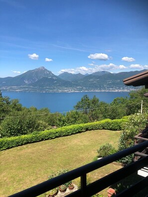 Un balcón con vistas a un lago, montañas y un cielo despejado.