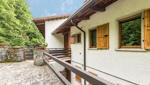 A stone-paved courtyard with a wooden staircase leading to a white building with wooden shutters and a balcony. - Cozy Apartment with Balcony, Lake View & Wi-Fi; Parking Available, Pets Welcome (San Zeno di Montagna)