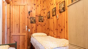 A wooden-paneled room with two beds, a wardrobe, and wall-mounted artwork. - Cozy Apartment with Balcony, Lake View & Wi-Fi; Parking Available, Pets Welcome (San Zeno di Montagna)