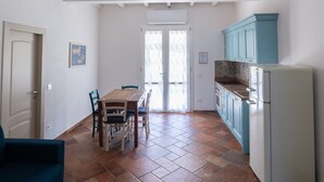 A kitchen with a dining table, chairs, and a refrigerator. - Apartment 'Il Rosmarino' with Sea View, Wi-Fi and Air Conditioning (Patresi)