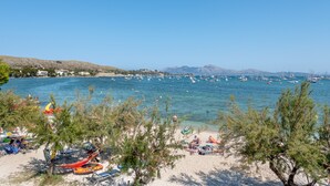 A beach with clear blue water, boats, and people.