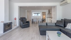 A modern living room with a fireplace, a sofa, a coffee table, and a dining area with chairs and a table.