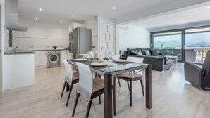 A modern apartment with a dining area, kitchen, and living space with a view.