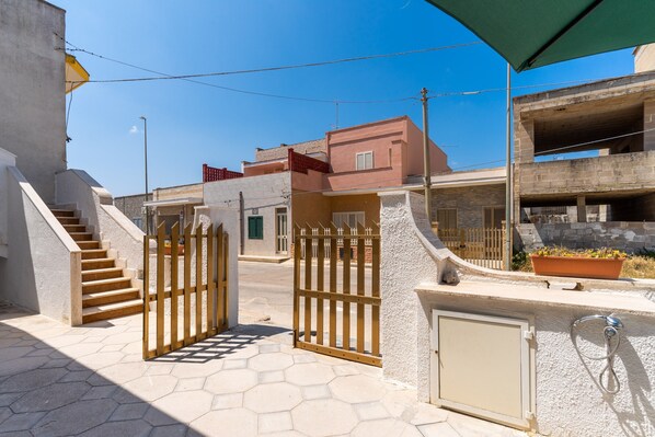 A gated entrance with a staircase, a potted plant, and a water feature.