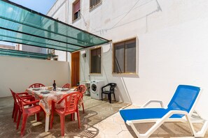 Un patio con tavolo e sedie, una lavatrice e una poltrona blu.