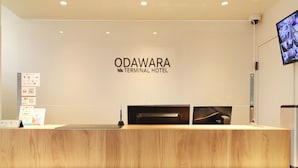 A reception desk at the ODAWARA TERMINAL HOTEL with a wooden counter, a digital screen, and a mounted camera. - Odawara Terminal Hotel (Odawara)
