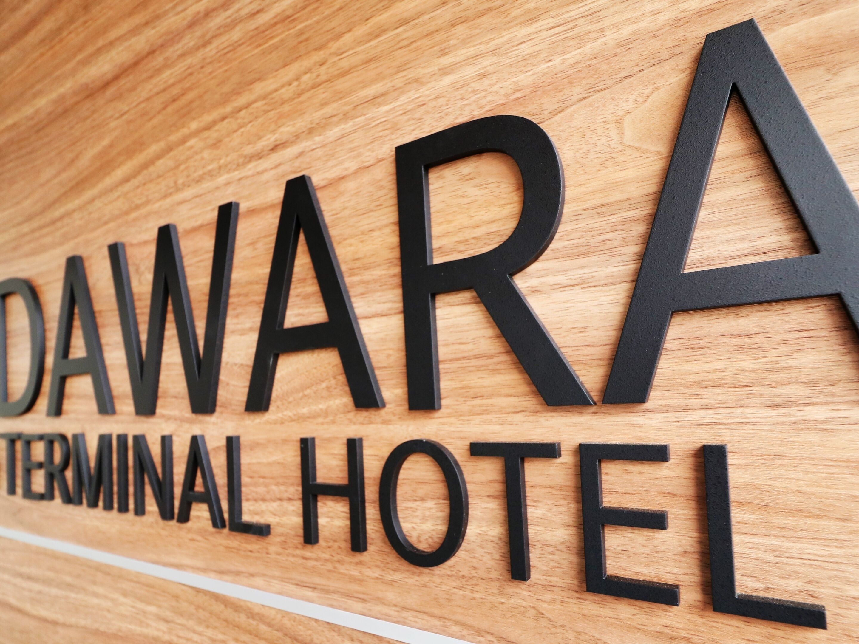 A wooden sign with the words "DAWARA TERMINAL HOTEL" in black letters.