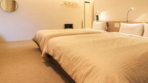 A hotel room with two beds, a round mirror, a coat rack, and a bedside table with a lamp. - Odawara Terminal Hotel (Odawara)