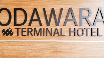Een houten bord met de tekst 'ODAWARA TERMINAL HOTEL' en een klein logo.