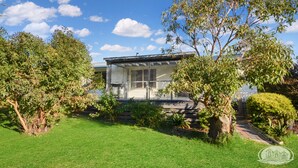 A modern house with a glass facade, surrounded by lush greenery and trees. - A quiet retreat just a stroll from the ocean (Allestree)
