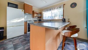 A kitchen with a refrigerator, stove, microwave, and wooden cabinets. - A quiet retreat just a stroll from the ocean (Allestree)