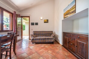 Une pièce comprenant un canapé, un meuble en bois et une table à manger avec des chaises.