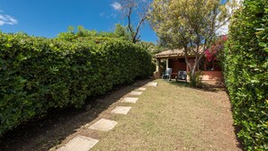 A garden pathway leading to a building with a tiled roof and a small patio area. - Holiday home on the sea, immersed in nature – Accu is Prezzus E special (Villasimius)