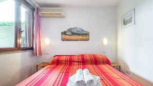 A hotel room with a bed, a painting on the wall, and a window with curtains. - Holiday home on the sea, immersed in nature – Accu is Prezzus E special (Villasimius)