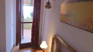 A room with a bed, a lamp, a painting, and a view through a window. - Sea View House Near the Beach – Casa Accu is Prezzus F (Villasimius)