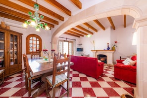 A dining area with a wooden table and chairs, a red sofa, a fireplace, and a checkered floor.